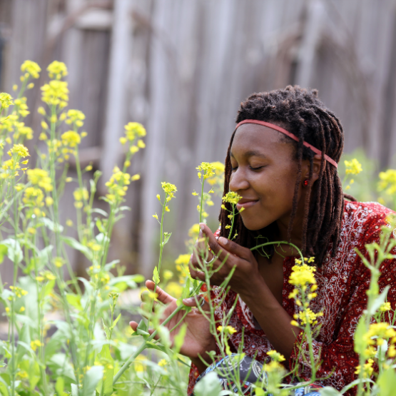A woman in a field of flowers smelling the fragrance