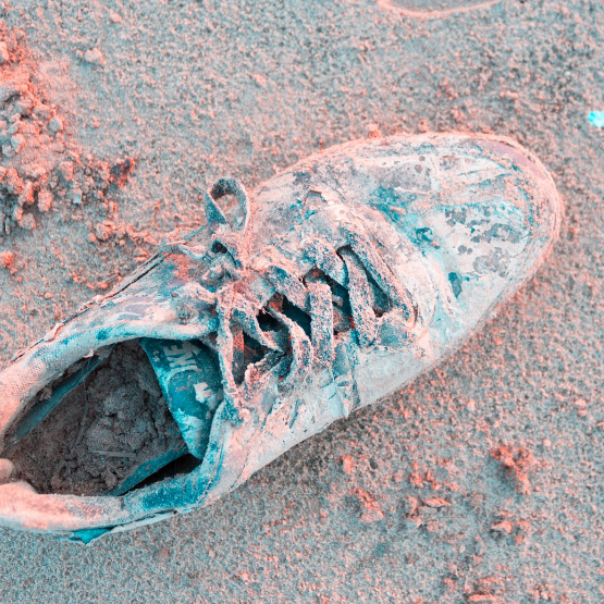 An old running shoe covered in sand